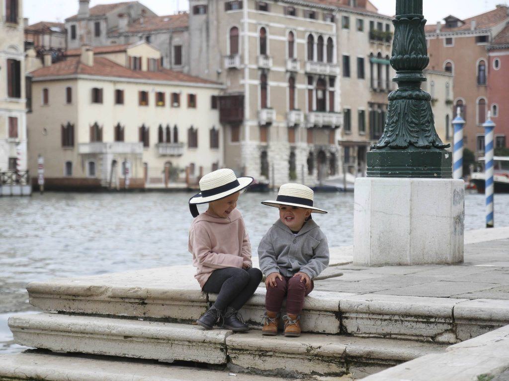 two girl and boy sitting on stairs near body of water