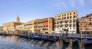 brown wooden boats at water near brown concrete buildings during daytime