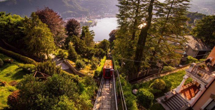 red train on rails between trees