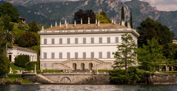 white and brown building in distance of mountain and body of water