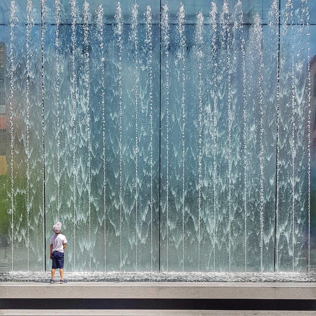 boy watching fountain during daytime