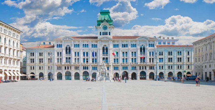 a large open Italian city square on a sunny day in Trieste surrounded by beautiful nineteenth century buildings